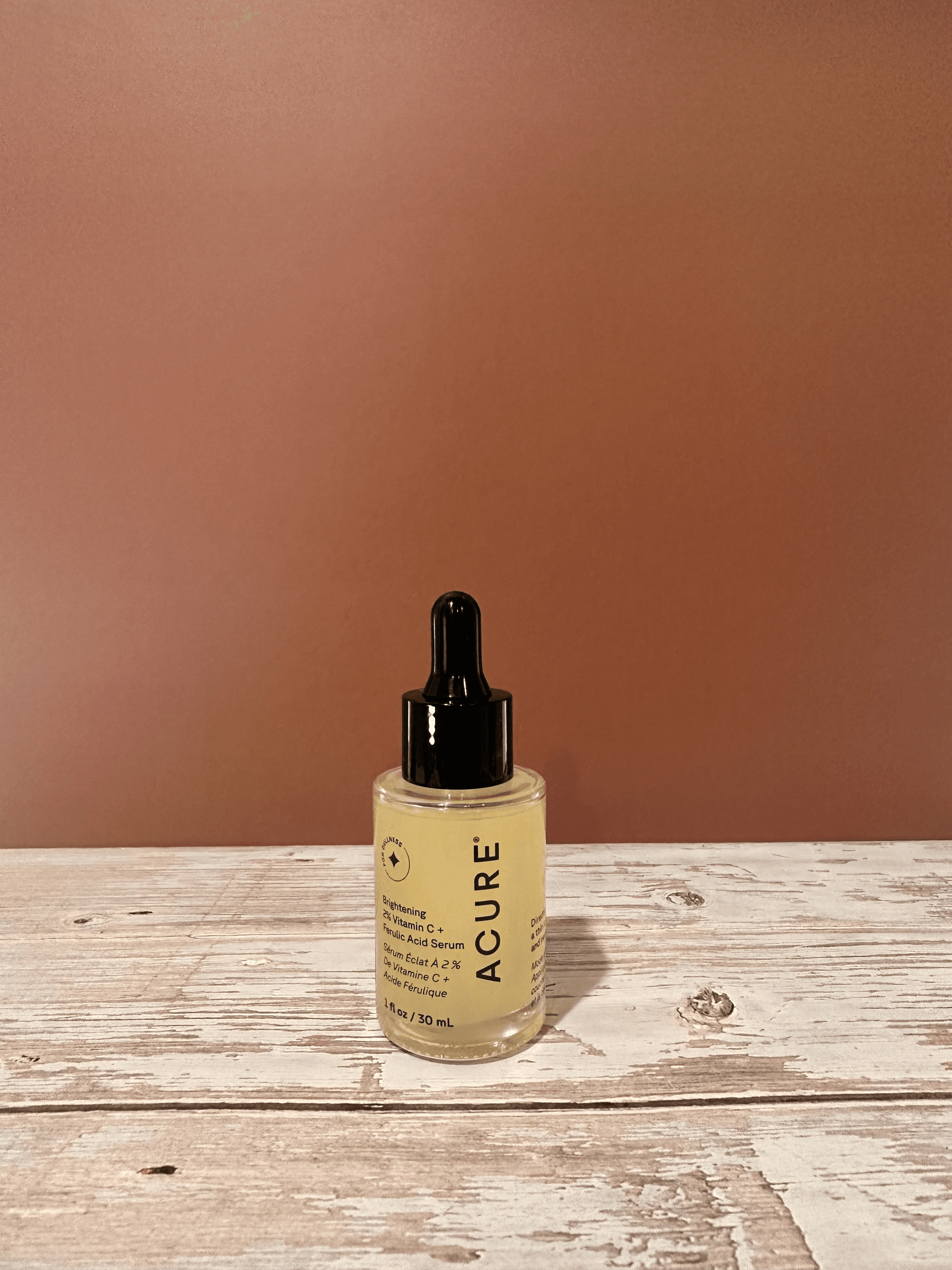 Acure Brightening Vitamin C + Ferulic Acid Serum, moisturizer, and mask on neutral linen fabric.